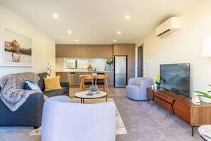 Ein modernes Wohnzimmer mit Sofa, Sesseln, Couchtisch und Flachbildfernseher.