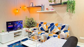 Una sala de estar moderna con un sofá, una mesa de centro, un televisor y plantas decorativas.