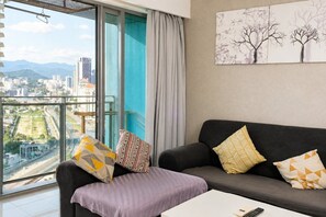 A modern living room with a sofa, pillows, a coffee table, and a city view through large windows. - Summer Suites KLCC by Moonlight (Kuala Lumpur)
