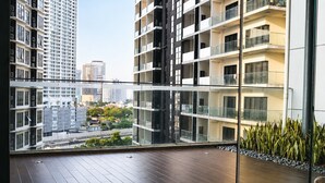 Un apartamento moderno con balcón, ventanas amplias y vistas de edificios circundantes.