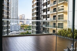Un apartamento moderno con balcón, ventanas amplias y vistas de edificios circundantes.