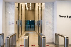 Un hall de ascensores moderno con paredes de mármol y un cartel que indica 'Tower B'.