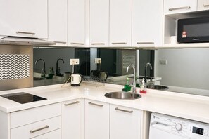 Una cocina moderna con armarios blancos, electrodomésticos de acero inoxidable y lavavajillas integrado.