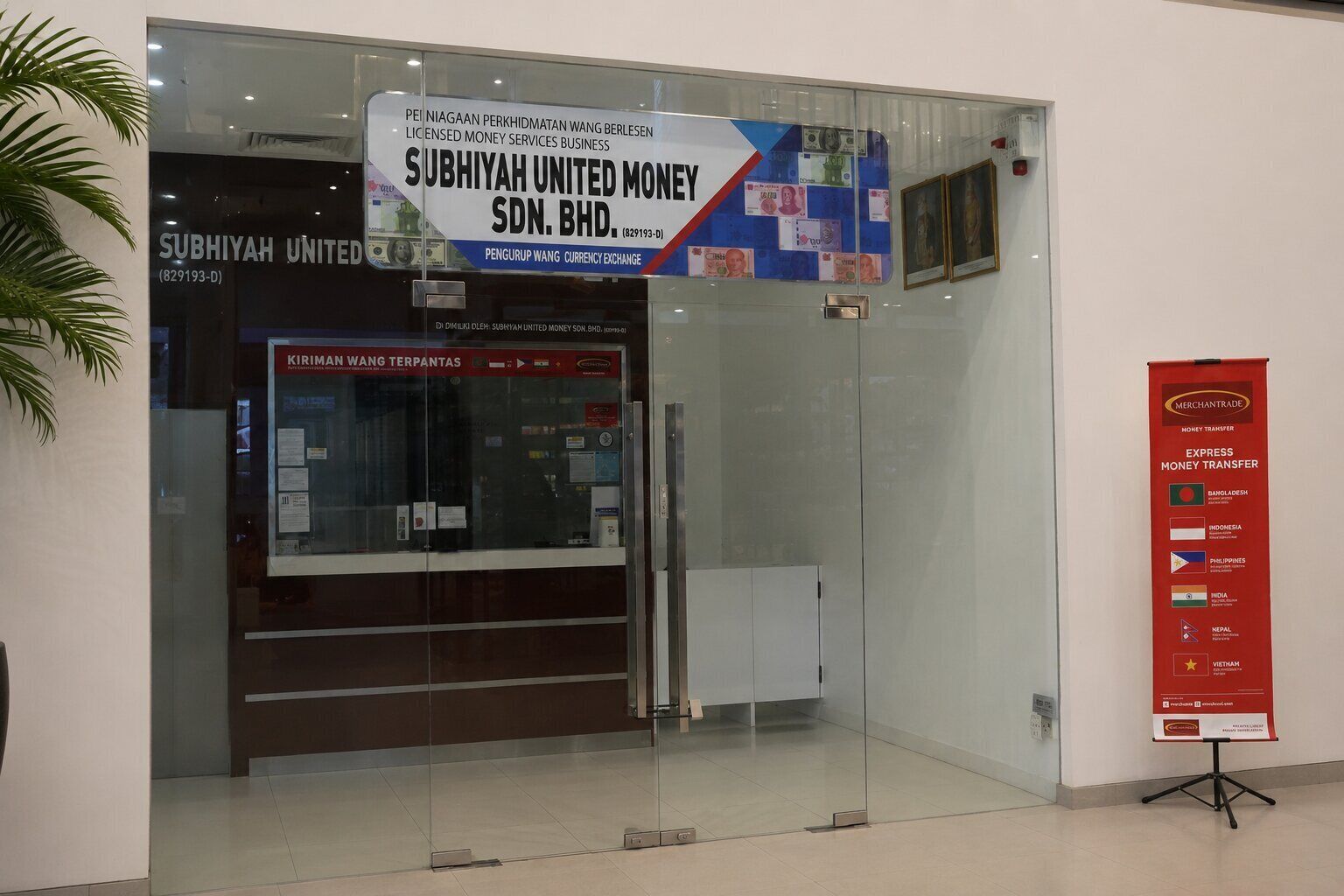A glass-fronted entrance to Subhiyah United Money Sdn. Bhd. with a sign for currency exchange services.