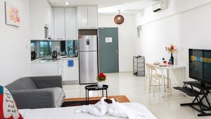 Un apartamento moderno con kitchenette, zona de comedor, sala de estar con sofá y televisor.