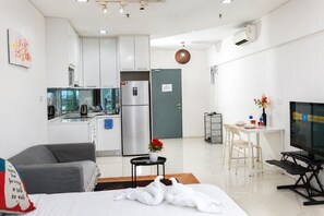 Un apartamento moderno con kitchenette, zona de comedor, sala de estar con sofá y televisor.