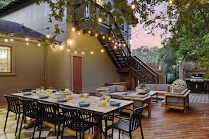 An outdoor dining area with a table set for four, surrounded by chairs, and a barbecue grill in the background. - On SoCo:Skyline, Sleeps 16, Game Room, Theater (Austin)