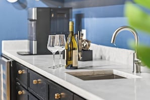 A kitchen with a marble countertop, a wine bottle, and glasses. - On SoCo:Skyline, Sleeps 16, Game Room, Theater (Austin)