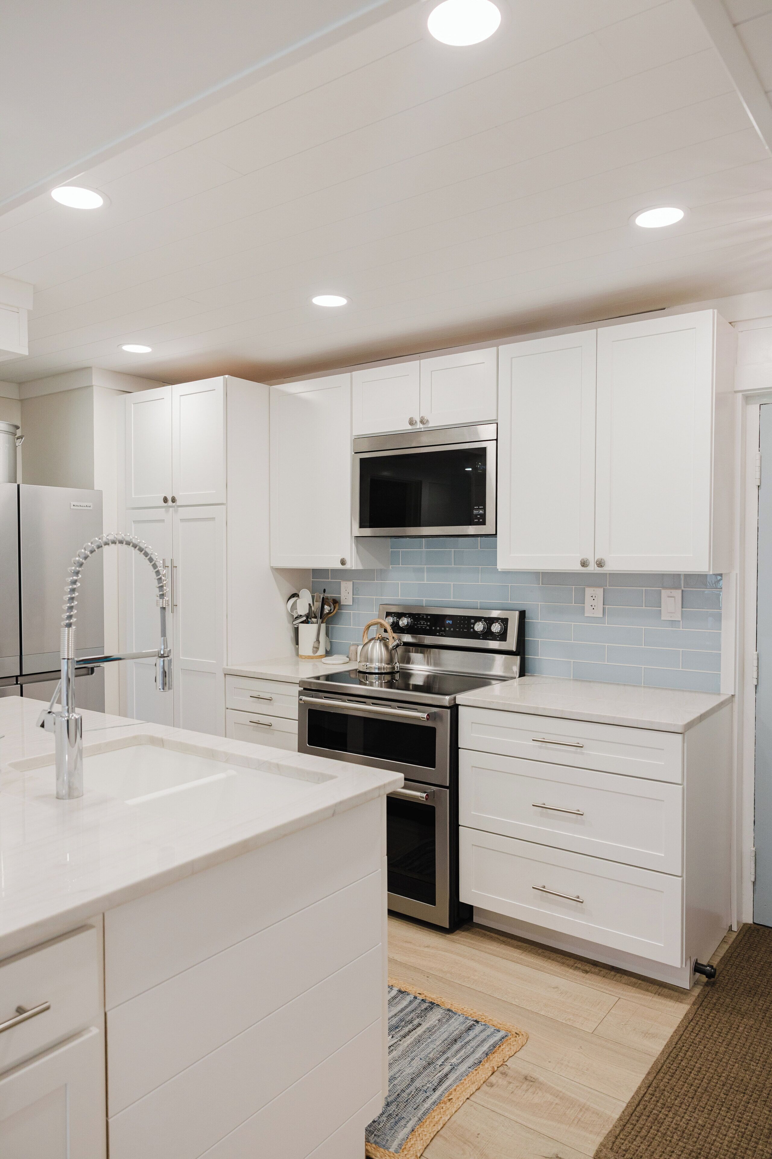 A modern kitchen with white cabinetry, stainless steel appliances, and a tiled backsplash.