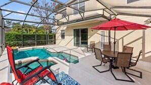 A covered outdoor swimming pool with a table and chairs, surrounded by a glass enclosure. - 6BR Private Pool Home at West Haven Gated Community (Davenport)