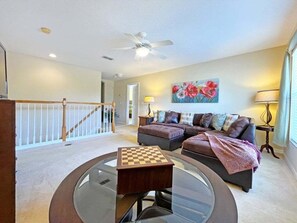 A living room with a glass coffee table, a sofa set, a painting, and a staircase. - 6BR Private Pool Home at West Haven Gated Community (Davenport)