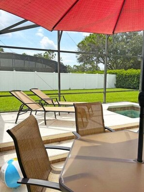 An outdoor patio with a table and chairs, a hot tub, and a covered seating area. - 6BR Private Pool Home at West Haven Gated Community (Davenport)