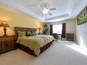 A bedroom with a bed, two bedside tables, a ceiling fan, a window with curtains, a plant, and a TV on the wall. - 6BR Private Pool Home at West Haven Gated Community (Davenport)