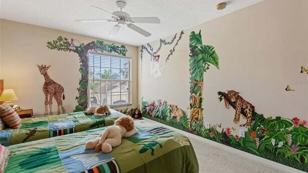 A room with two beds, a ceiling fan, a window with blinds, and a mural of jungle animals. - 6BR Private Pool Home at West Haven Gated Community (Davenport)