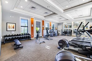 A gym with various exercise equipment, including treadmills, weight machines, and dumbbells. - Lanai Luxury - Solterra - Modern Retreat With Private Pool, Lanai, Central AC & gas Grill (Davenport)