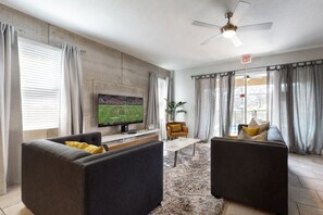 A modern living room with a flat-screen TV, two sofas, a coffee table, and a ceiling fan. - Lanai Luxury - Solterra - Modern Retreat With Private Pool, Lanai, Central AC & gas Grill (Davenport)
