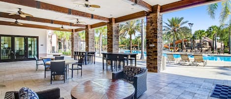 Un patio al aire libre con asientos, piscina y vistas a un parque acuático.