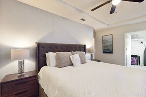 A hotel room with a large bed, two bedside tables, a ceiling fan, and a painting on the wall. - Lanai Luxury - Solterra - Modern Retreat With Private Pool, Lanai, Central AC & gas Grill (Davenport)