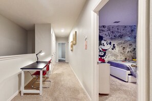 A hallway with a desk, chair, and a bed with a cartoon character mural. - Lanai Luxury - Solterra - Modern Retreat With Private Pool, Lanai, Central AC & gas Grill (Davenport)