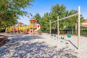 A playground with a slide, swings, and climbing structures. - Lanai Luxury - Solterra - Modern Retreat With Private Pool, Lanai, Central AC & gas Grill (Davenport)
