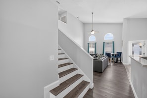 A modern interior with a staircase, a dining area, and a kitchen. - Golden Light Retreat-spacious 5BR Pool Home Near Disney (Davenport)