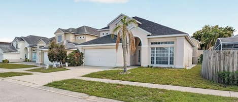 A residential area with single-family homes featuring front yards, driveways, and a clear sky.