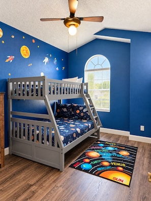 A child's bunk bed room with a starry wall, a ceiling fan, and a space-themed rug. - Golden Light Retreat-spacious 5BR Pool Home Near Disney (Davenport)