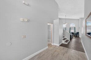 A modern interior with a staircase leading to a dining area, light grey walls, and a wooden floor. - Golden Light Retreat-spacious 5BR Pool Home Near Disney (Davenport)