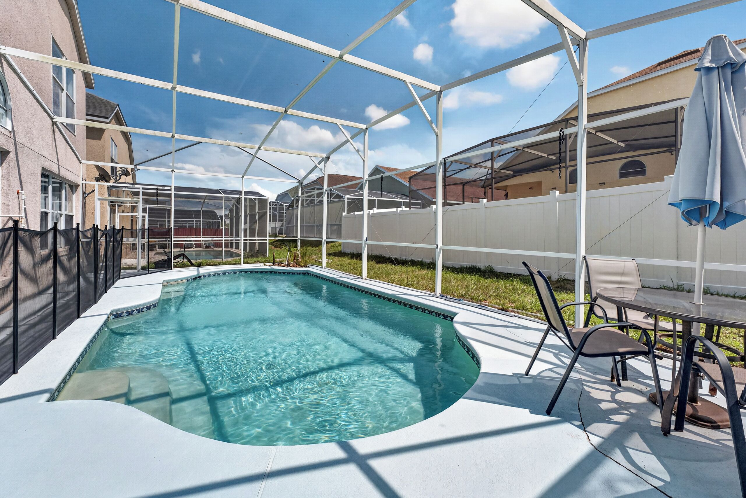 A swimming pool with a white deck and a glass enclosure.