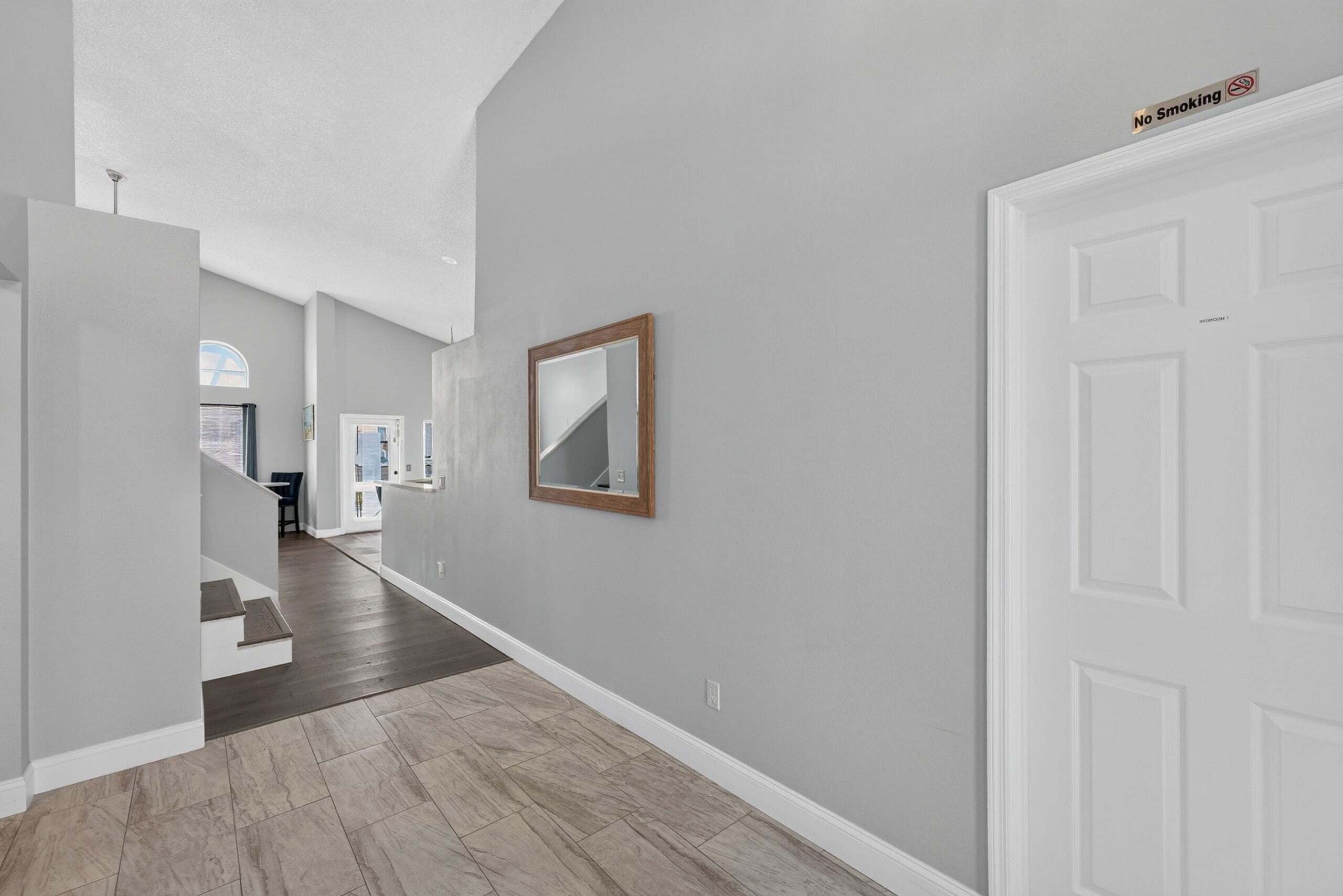 A hallway with a wooden floor, a white door, and a 'No Smoking' sign on the wall.