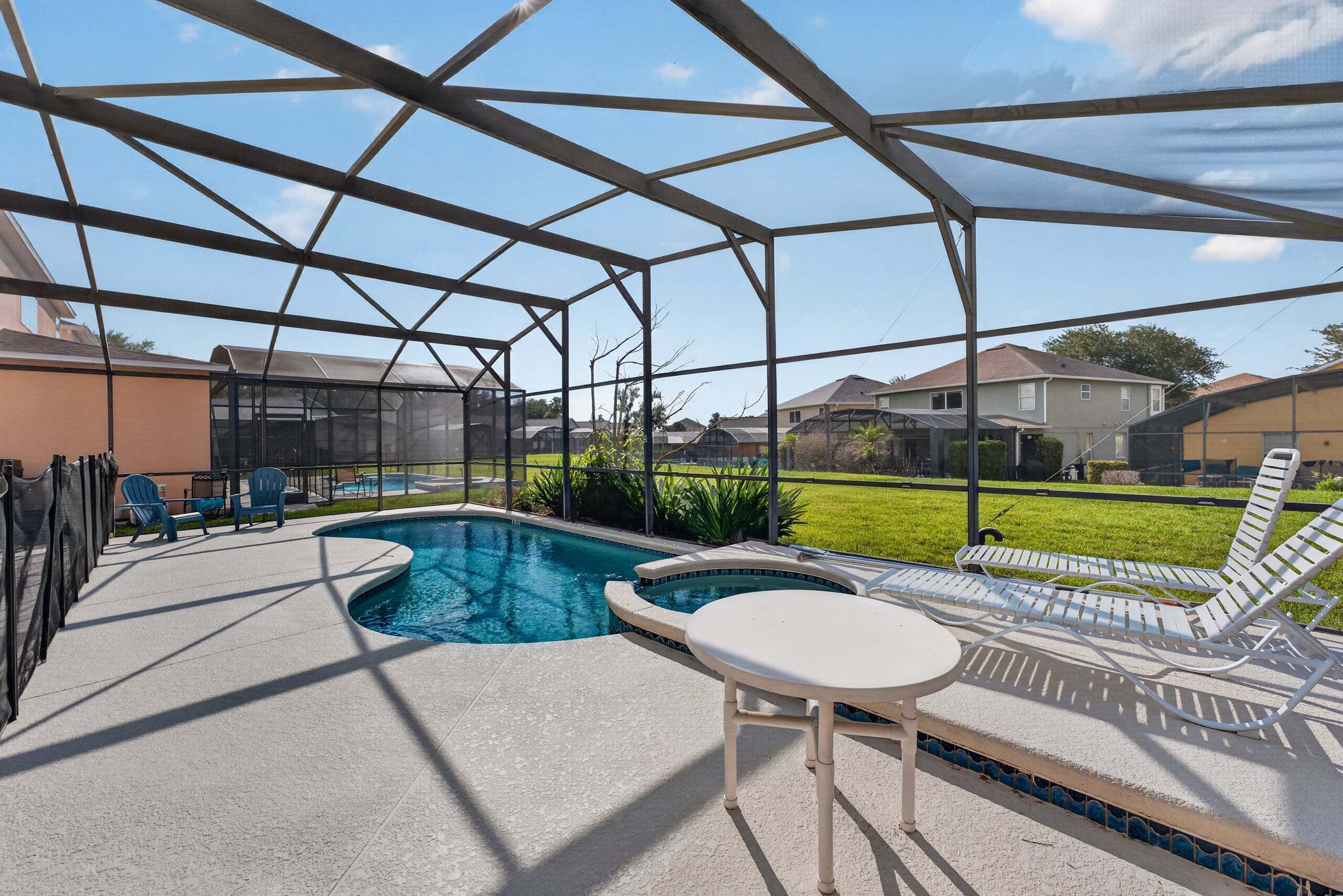 A covered outdoor swimming pool with lounge chairs and a table.