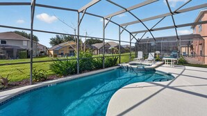 A swimming pool with a covered area, surrounded by houses, and a clear sky. - Emerald Magic Retreat - Minutes to Disney! Emerald Island Pool Home Retreat (Kissimmee)
