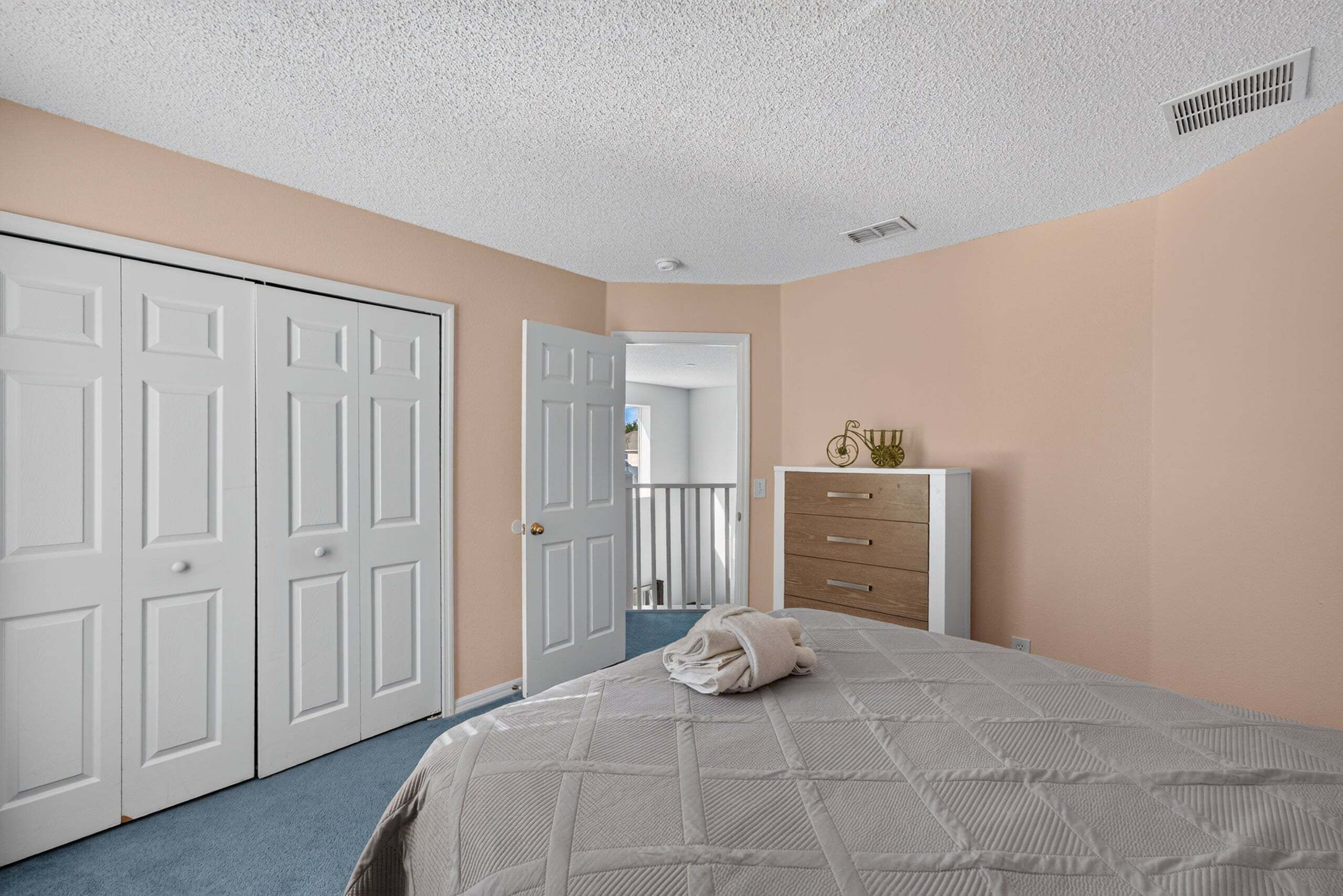 Quarto com cama, cômoda, armário e porta para outro espaço.