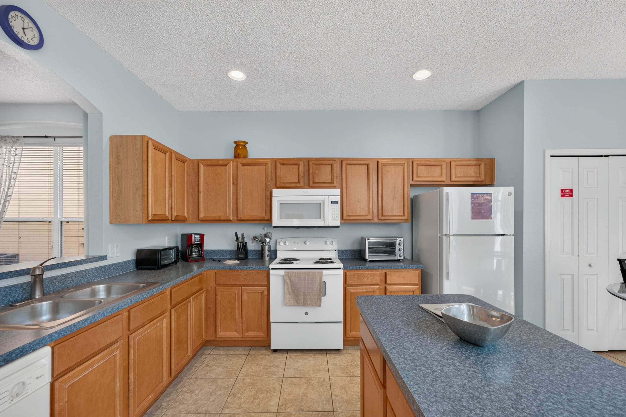 A kitchen with wooden cabinets, a white stove, a microwave, a toaster, and a refrigerator.