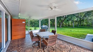 A covered patio with a table and chairs, large windows, and a ceiling fan. - Kis105-2601-4-pg - Shingle Creek Poolside Retreat (Kissimmee)