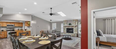 A spacious living area with a dining table, kitchen, and a fireplace.
