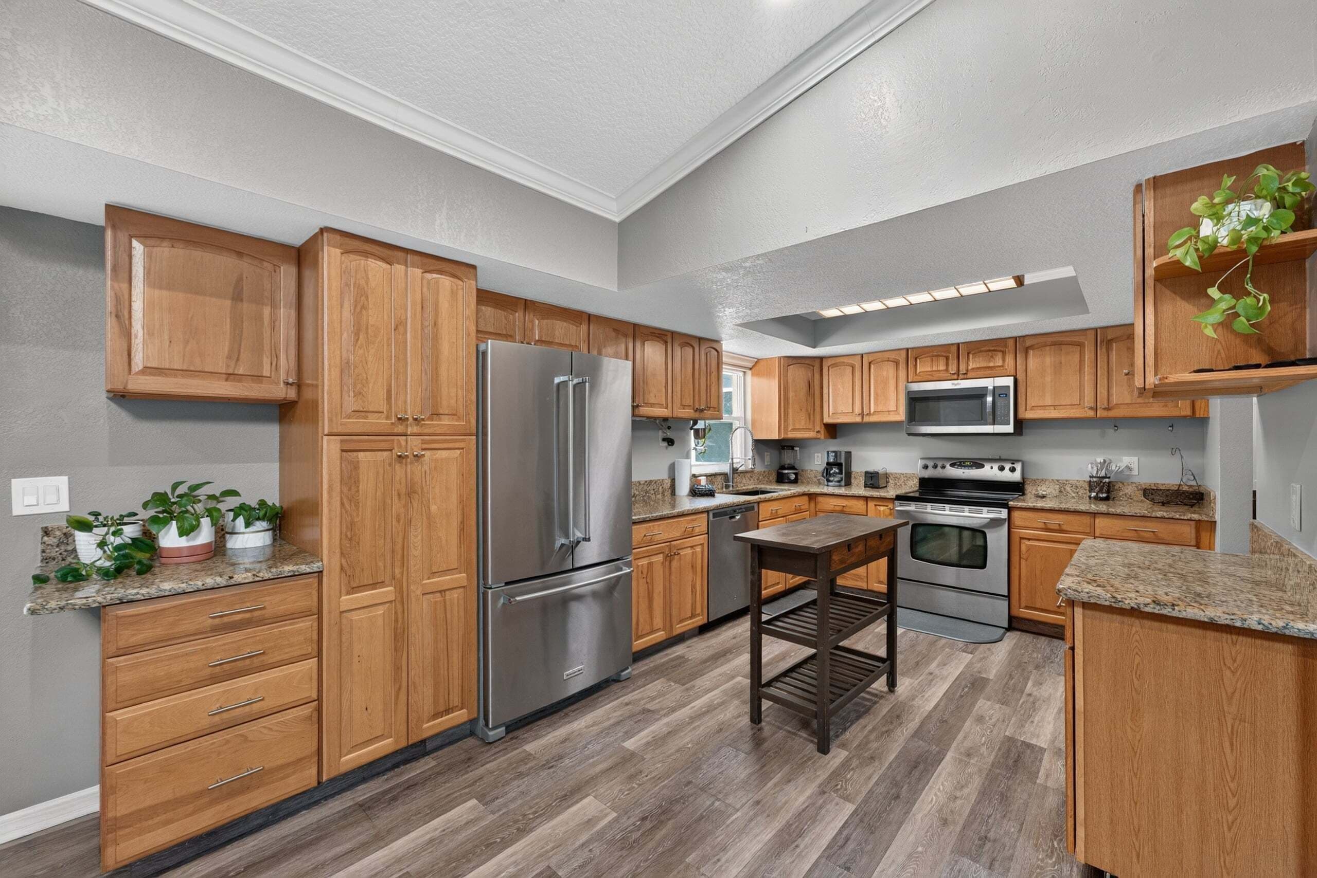 A modern kitchen with wooden cabinets, stainless steel appliances, and a granite countertop.