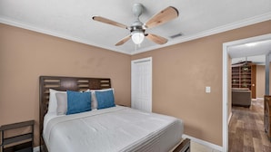 A bedroom with a bed, a ceiling fan, a nightstand, and a door leading to another room. - Kis105-2601-4-pg - Shingle Creek Poolside Retreat (Kissimmee)