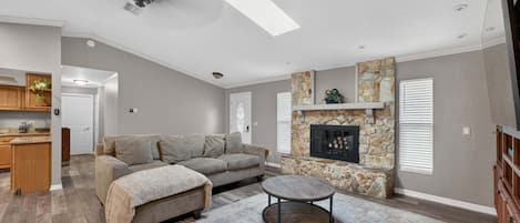 A modern living room with a sectional sofa, a fireplace, and a dining area with wooden cabinets.