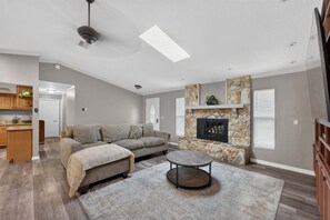 A modern living room with a sectional sofa, a fireplace, and a dining area with wooden cabinets. - Kis105-2601-4-pg - Shingle Creek Poolside Retreat (Kissimmee)