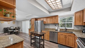 A modern kitchen with wooden cabinets, stainless steel appliances, and a skylight. - Kis105-2601-4-pg - Shingle Creek Poolside Retreat (Kissimmee)