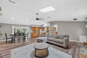 A spacious living room with a gray sofa, a round coffee table, and a dining area with a wooden table and chairs. - Kis105-2601-4-pg - Shingle Creek Poolside Retreat (Kissimmee)