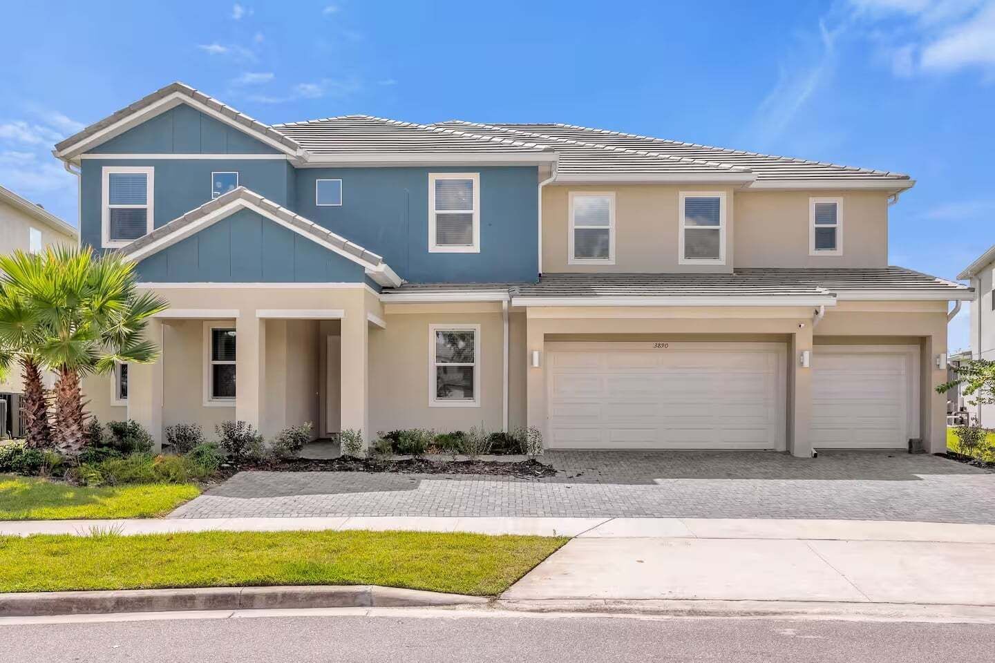 A two-story residential building with a garage, a covered driveway, and a well-maintained lawn.