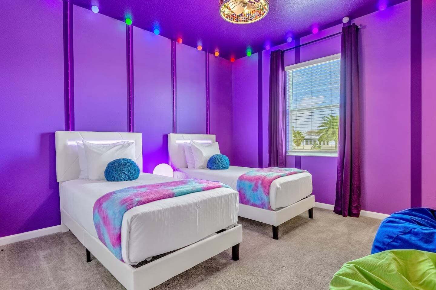 Une chambre avec deux lits, une fenêtre avec des rideaux et un luminaire au plafond.