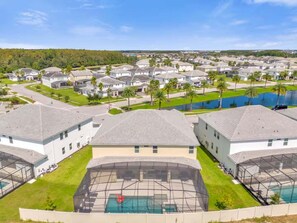 A residential area with multiple houses, a swimming pool, and a clear sky.