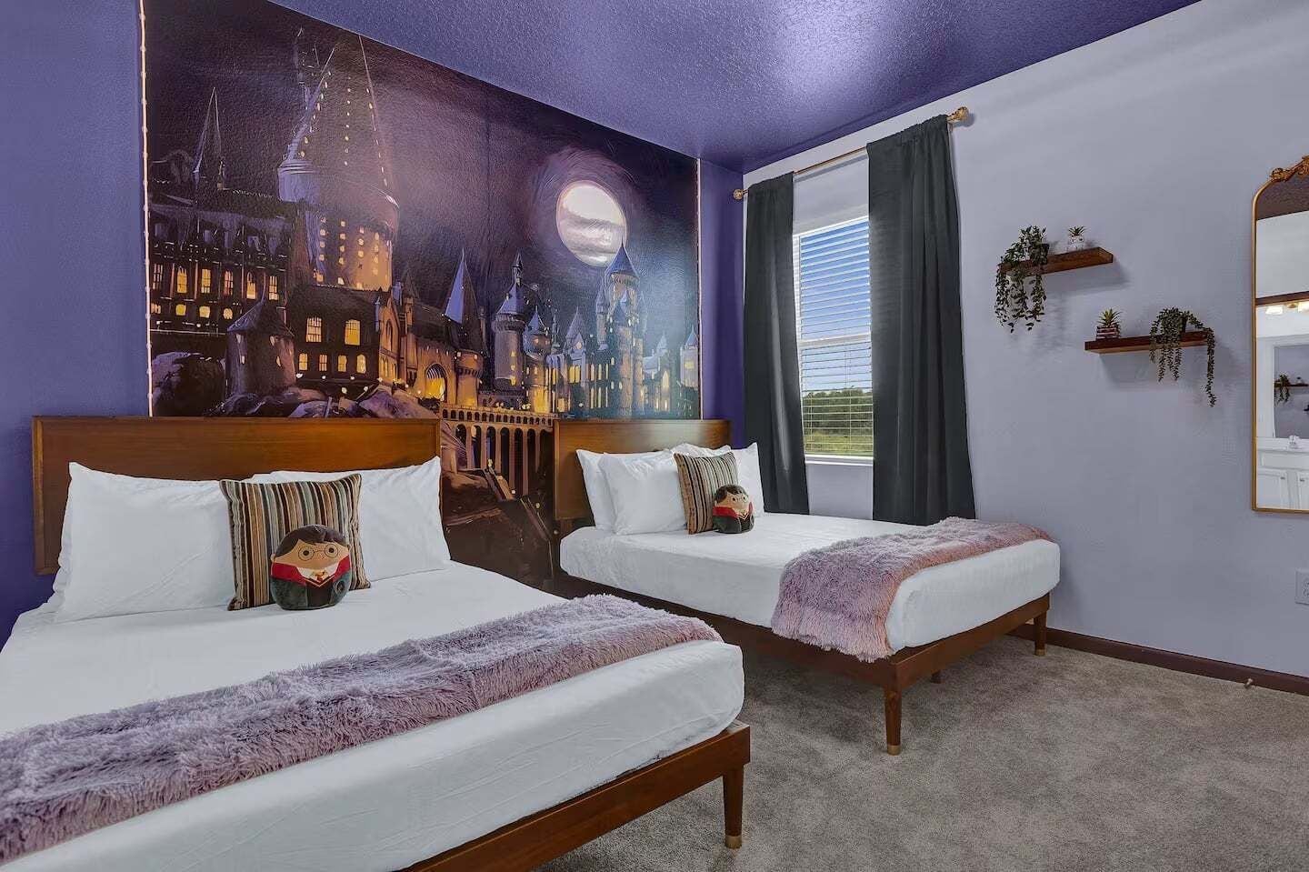Une chambre d’hôtel avec deux lits, une grande fresque représentant un paysage urbain, une fenêtre avec des rideaux et un miroir sur le mur.