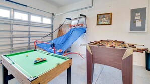 Una habitación con mesa de billar, mesa de fútbol y una red de escalada azul.