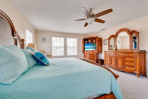 A bedroom with a bed, a dresser, a television, and a ceiling fan. - King's Way Haven - 7BR Golf-view Home With Pool and Game Room (Davenport)