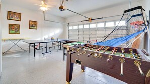 Una habitación con mesa de fútbol de mesa, mesa de ping pong y ventilador de techo.