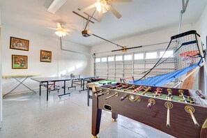 A room with a foosball table, ping pong table, and a ceiling fan. - King's Way Haven - 7BR Golf-view Home With Pool and Game Room (Davenport)